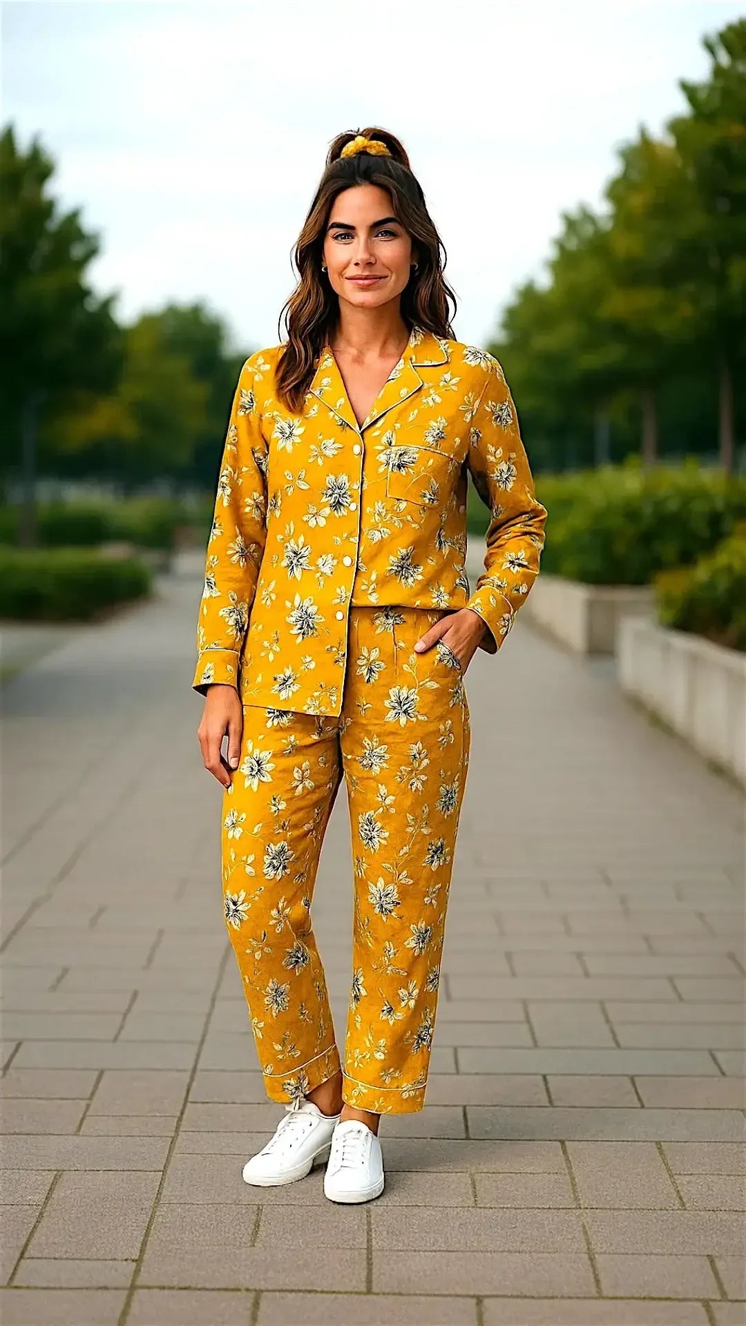 Woman wearing yellow floral pajama set with white sneakers standing outdoors on paved walkway